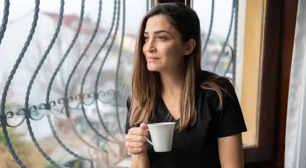Woman holding coffee looking thoughtful during reflective moment